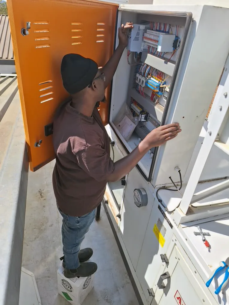 Technician inspecting a rooftop HVAC control panel